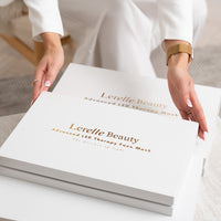 Person holding a box of Lerelle Beauty advanced LED therapy face mask on a white surface.